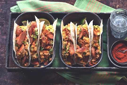 Two dishes of three flour tortilla tacos filled with Quorn Sausage, eggs, and cheese.