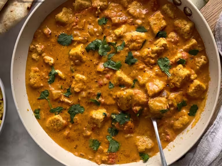 Vegetarian Quorn pieces curry in a dish garnished with coriander and served with a spoon.