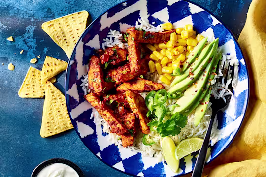 Vegetarian taco salad with Quorn sliced fillets served in a blue bowl with sour cream and nacho chips on the side.
