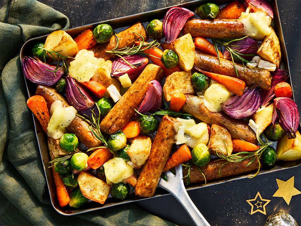A traybake of vegetarian sausage with root vegetables of carrots, potatoes, brussels sprouts, onions and parsnips.