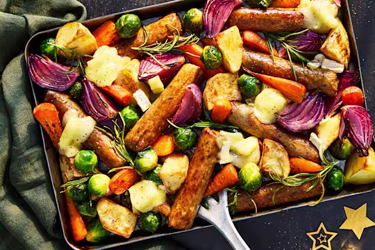 A traybake of vegetarian sausage with root vegetables of carrots, potatoes, brussels sprouts, onions and parsnips.