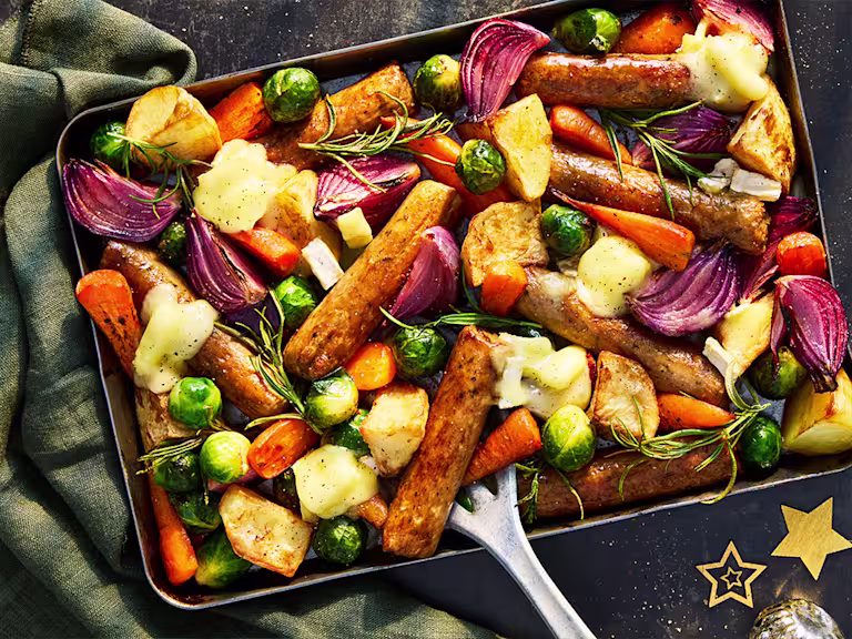 A traybake of vegetarian sausage with root vegetables of carrots, potatoes, brussels sprouts, onions and parsnips.