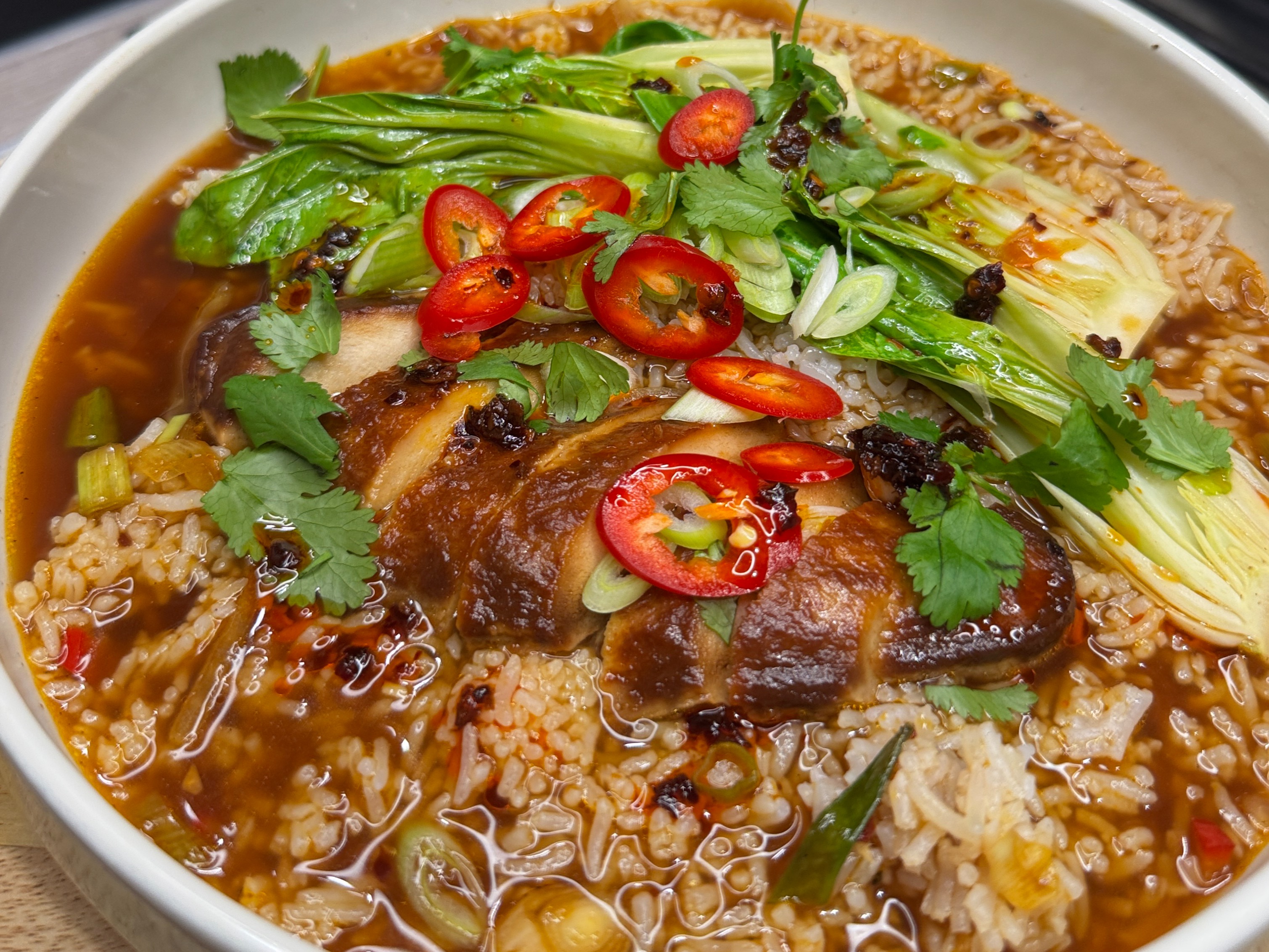 Quorn Fillets in a vegetable broth with rice, pak choi, spring onions, coriander and chilli served in a bowl.