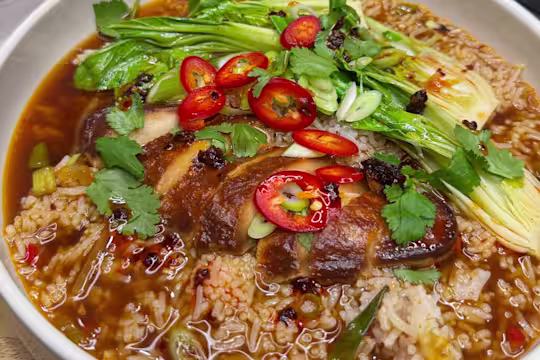 Quorn Fillets in a vegetable broth with rice, pak choi, spring onions, coriander and chilli served in a bowl.