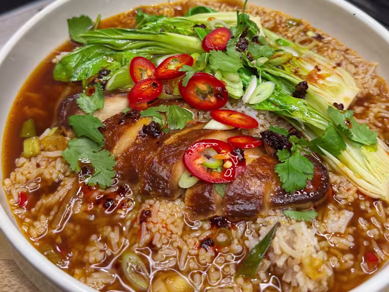 Quorn Fillets in a vegetable broth with rice, pak choi, spring onions, coriander and chilli served in a bowl.