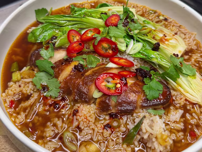 Quorn Fillets in a vegetable broth with rice, pak choi, spring onions, coriander and chilli served in a bowl.