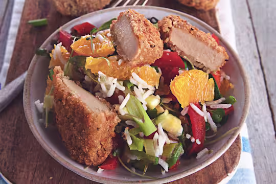 A salad made with lettuce, rice, orange segments, red pepper, cucumber and spring onions topped with Quorn Southern Fried Bites and herbs.