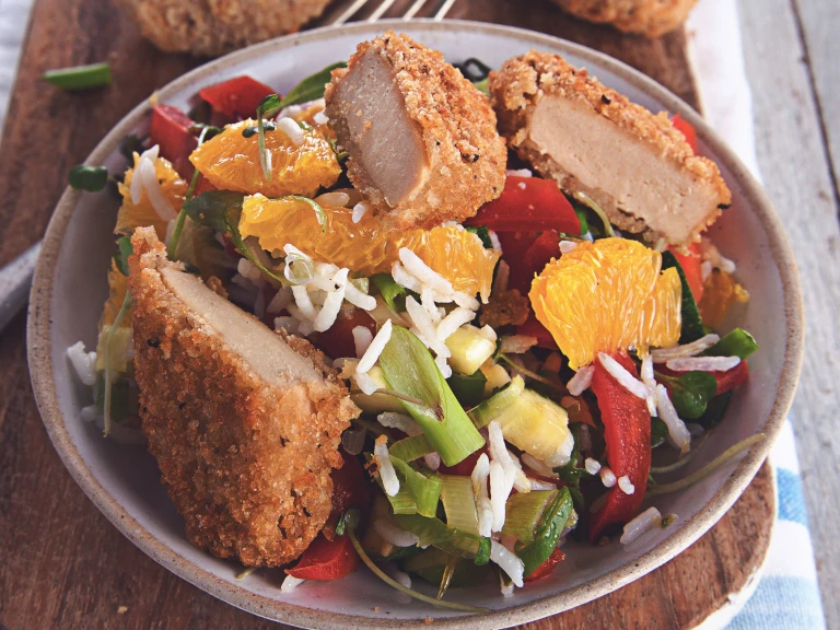 A salad made with lettuce, rice, orange segments, red pepper, cucumber and spring onions topped with Quorn Southern Fried Bites and herbs.
