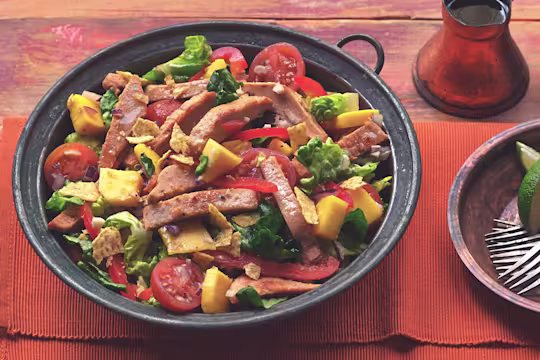 A serving bowl filled with mango salad topped with Quorn Roast Mini Fillets.