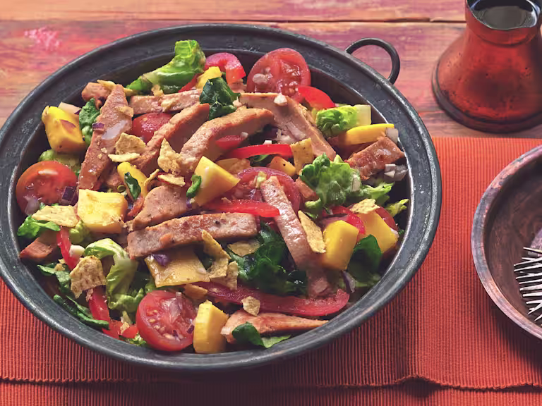 A serving bowl filled with mango salad topped with Quorn Roast Mini Fillets.