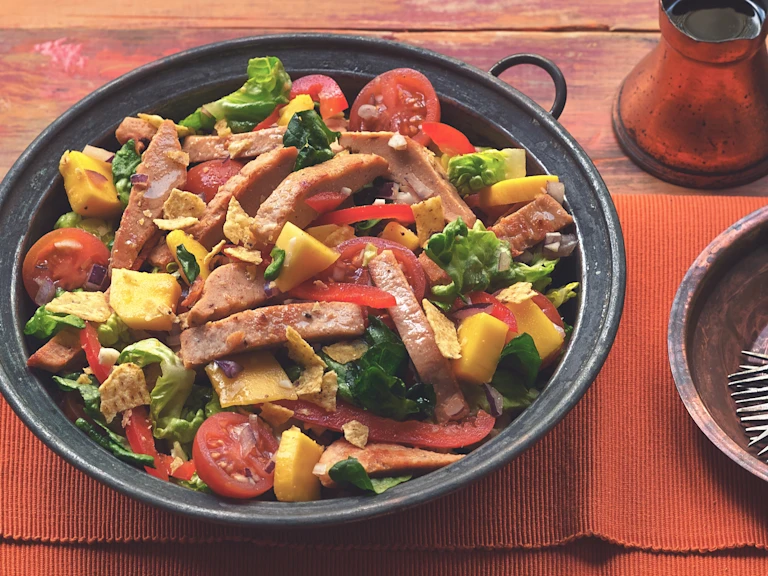 A serving bowl filled with mango salad topped with Quorn Roast Mini Fillets.