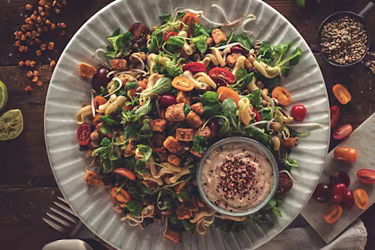 Picknick Vegetarisk sallad toppad med Quornbitar och hummus vid sidan.
