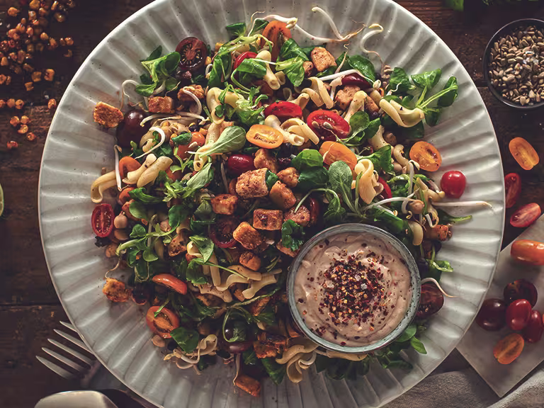 Picknick Vegetarisk sallad toppad med Quornbitar och hummus vid sidan.