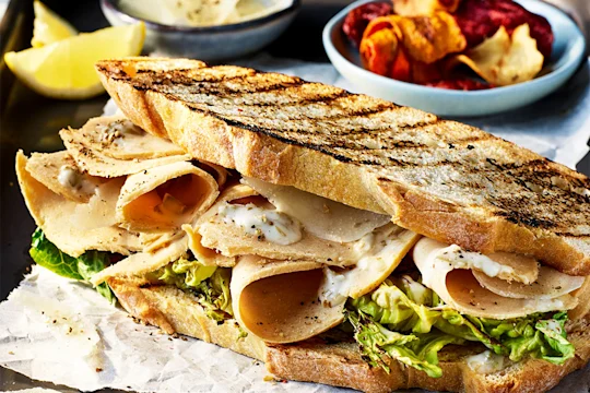 Toasted sourdough bread sandwich with Quorn Vegan Chicken Slices, Caesar dressing and salad leaves with a side of vegetable crisps.