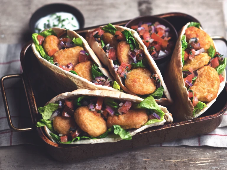 A tray of kebab style Quorn Meat Free Crispy Nuggets served in pitta bread with a yoghurt dip.