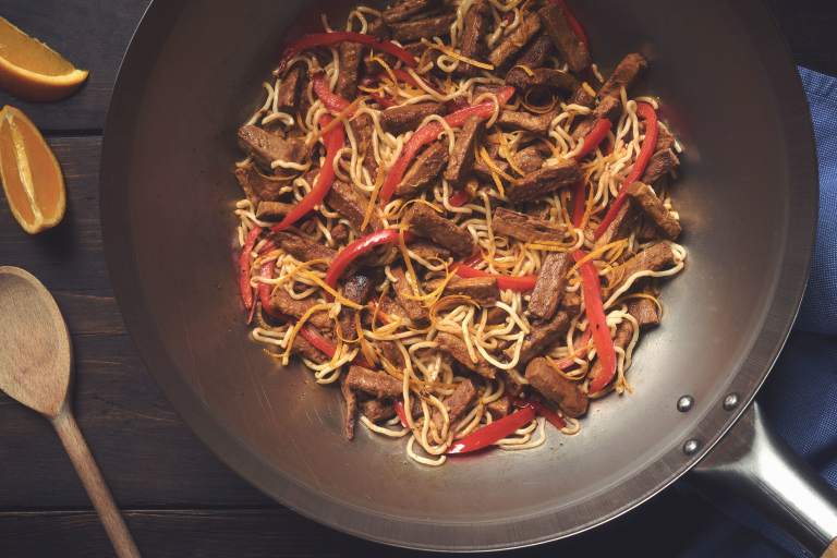 A pan full of steak strip and sesame stir fry made with Quorn Vegetarian Steak Strips, egg noodles, and red peppers.