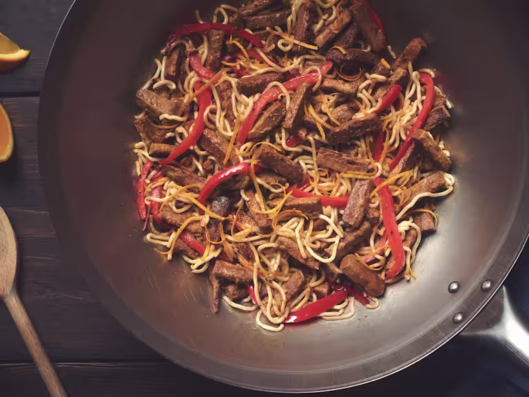 A pan full of steak strip and sesame stir fry made with Quorn Vegetarian Steak Strips, egg noodles, and red peppers.