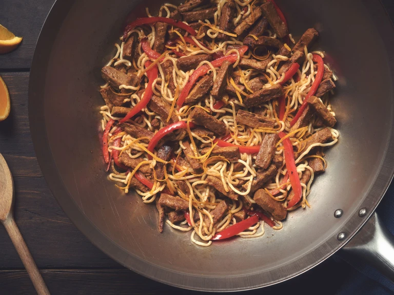 A pan full of steak strip and sesame stir fry made with Quorn Vegetarian Steak Strips, egg noodles, and red peppers.