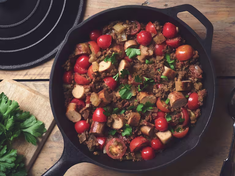 A lentil salad made with Quorn Sausages and tomatoes topped with parsley in a skillet.