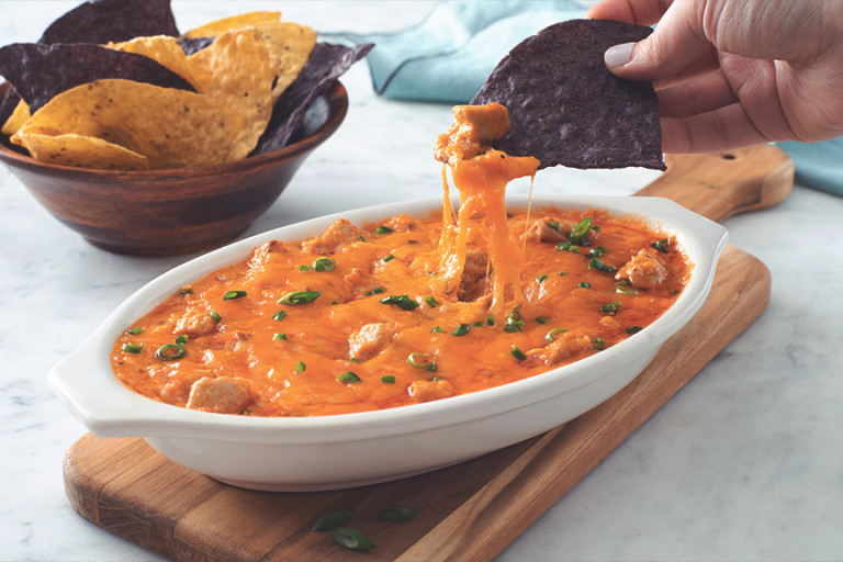 Vegetarian Quorn Buffalo Chicken Dip served in a dish with a nacho being dipped into the sauce