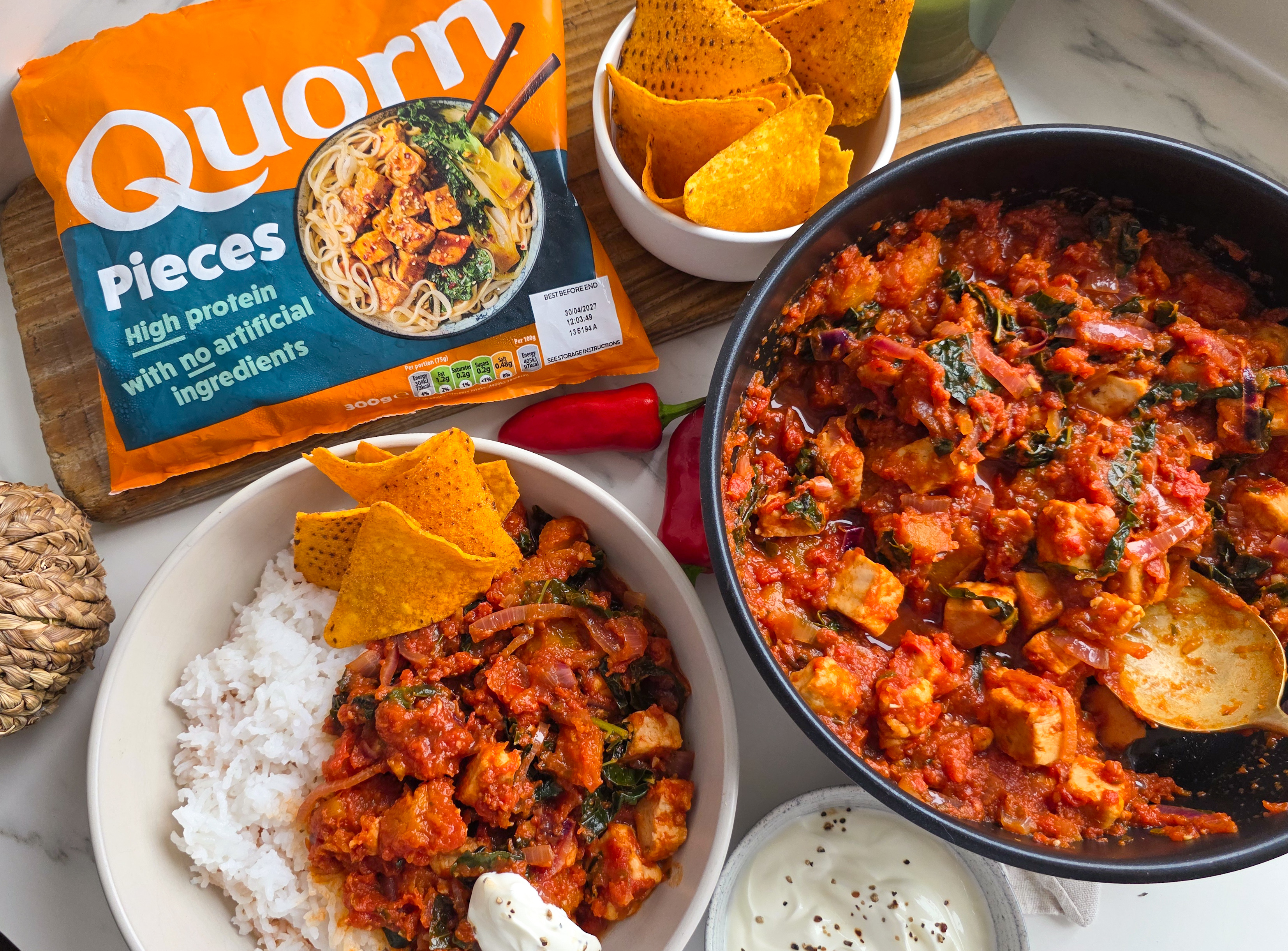 A bag of Quorn Pieces with two bowls of chilli and rice. 
