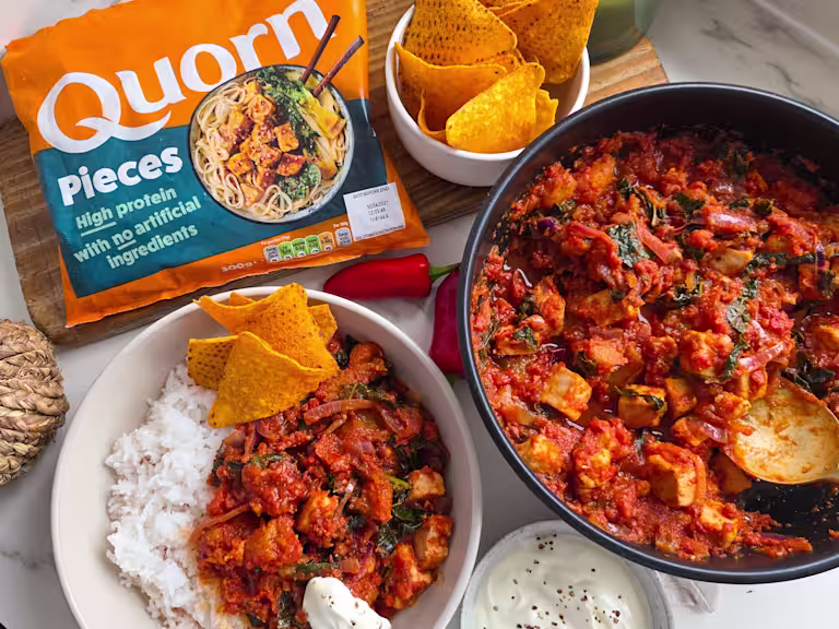 A bag of Quorn Pieces with two bowls of chilli and rice.