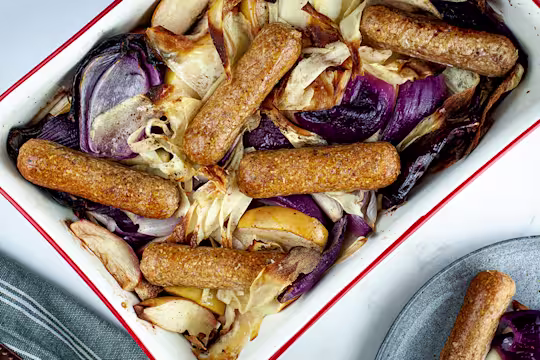 Vegan fruit apple and sausage tray bake with Quorn's Brilliant Bangers served in a baking tray.