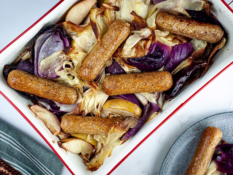 Vegan fruit apple and sausage tray bake with Quorn's Brilliant Bangers served in a baking tray.