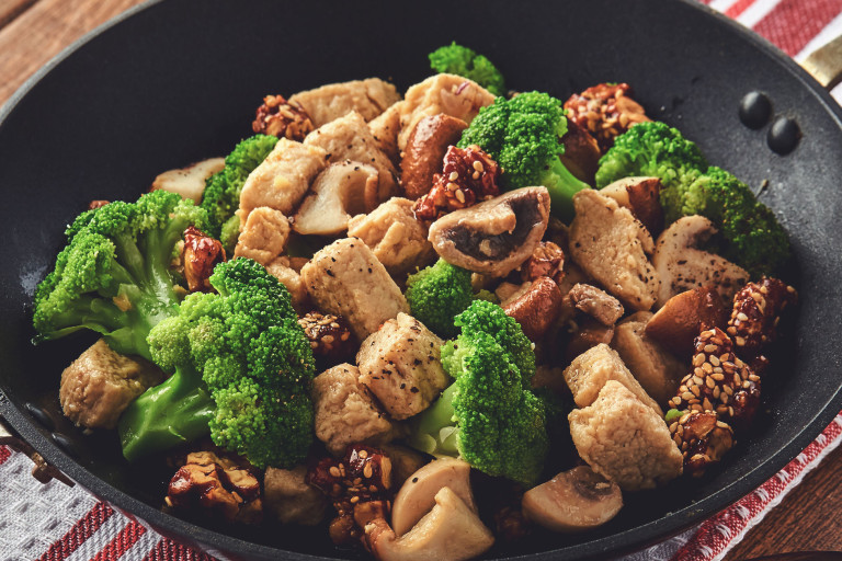 A skillet filled with a stir fry of Quorn Pieces, broccoli, mushrooms, and candied walnuts.