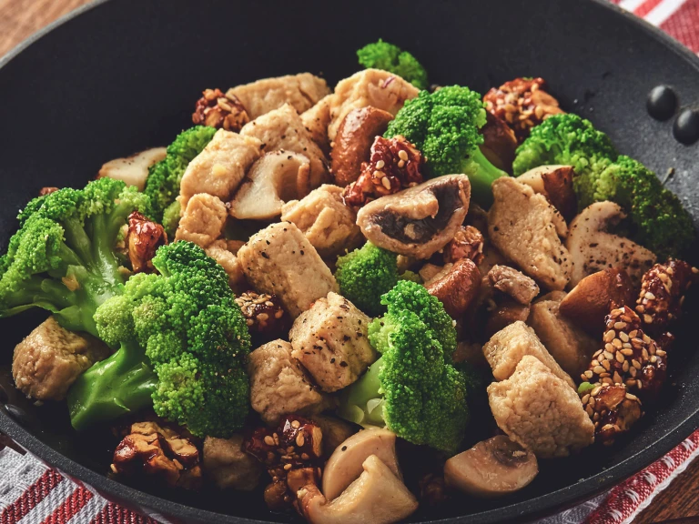 A skillet filled with a stir fry of Quorn Pieces, broccoli, mushrooms, and candied walnuts.