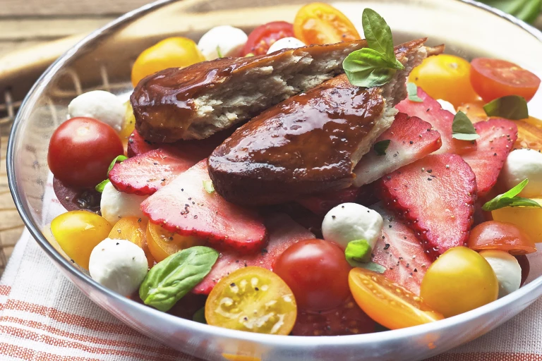 A salad of strawberries, tomatoes, mozzarella, and basil topped with Quorn Fillets glazed with Pimm's.