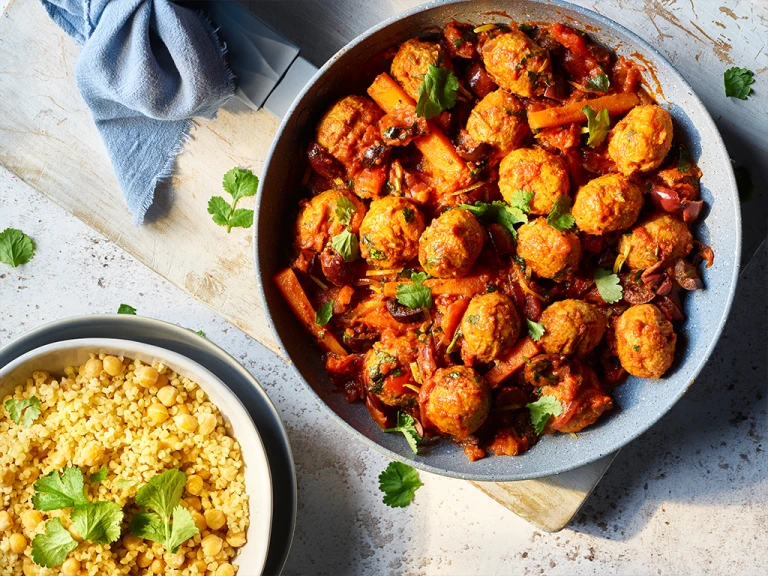 Spiced Quorn meatless meatball tagine with bulgur wheat and chickpeas served in two bowls. 