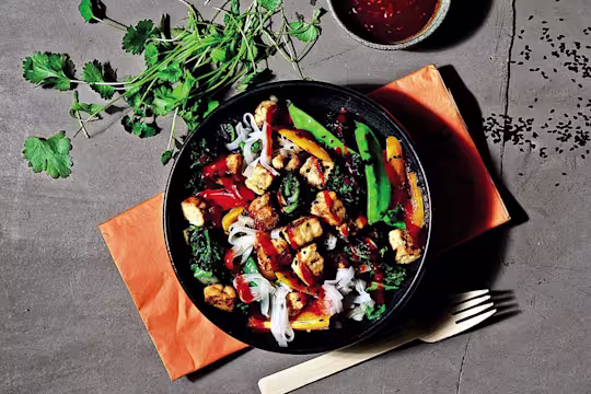 Vegetarian Quorn Pieces stir fry with peppers, baby corn and asparagus with a side of noodles, served on a plate