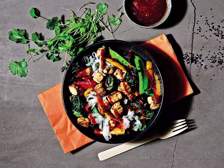 Vegetarian Quorn Pieces stir fry with peppers, baby corn and asparagus with a side of noodles, served on a plate