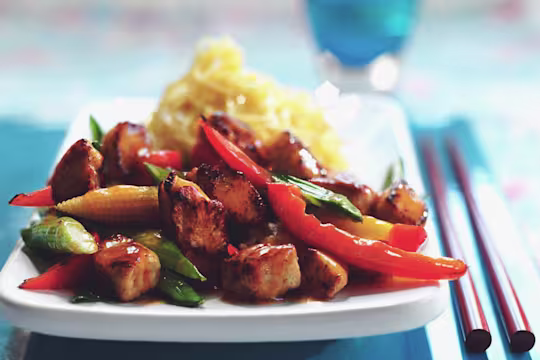 Vegetarian Quorn Pieces stir fry with peppers, baby corn and asparagus with a side of noodles, served on a plate