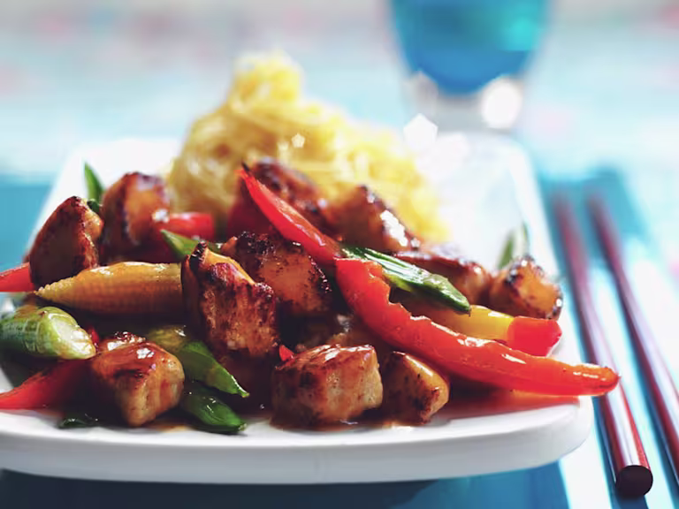 Vegetarian Quorn Pieces stir fry with peppers, baby corn and asparagus with a side of noodles, served on a plate