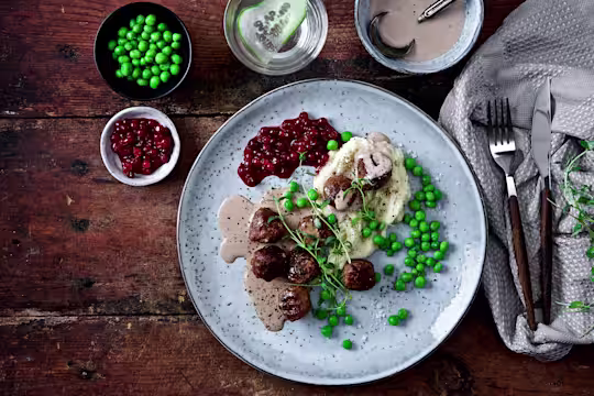 Veganska köttbullar med mos, gräddsås och rårörda lingon på tallrik.