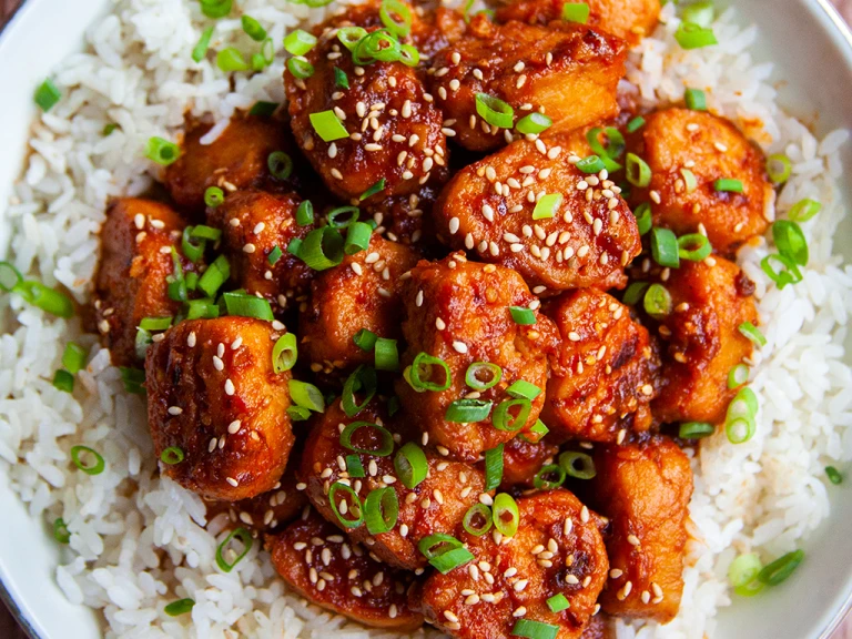 A bowl of vegetarian sticky sesame chicken made using Quorn Fillet Pieces served on top of a bowl of rice. 