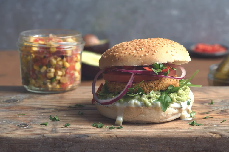 Vegan burger made with Quorn Vegan Hot and Spicy Burgers with salad, smashed avocado, tomato and onion in a bun