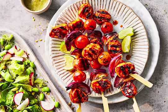 Three vegetarian skewers made with a Quorn fillet pieces served with a tray of green goddess salad.