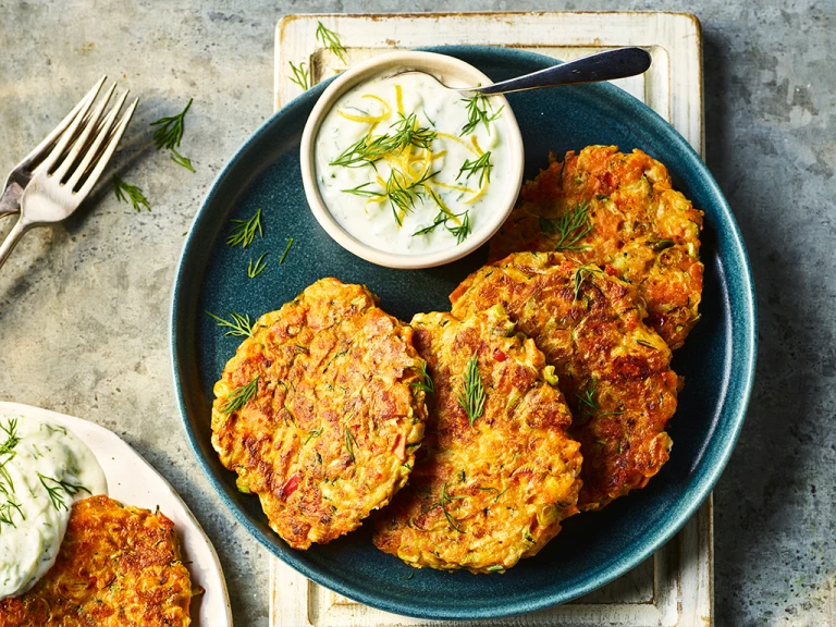 Four Quorn Smoky Ham Free Vegan Fritters served alongside a dip on a blue dish.