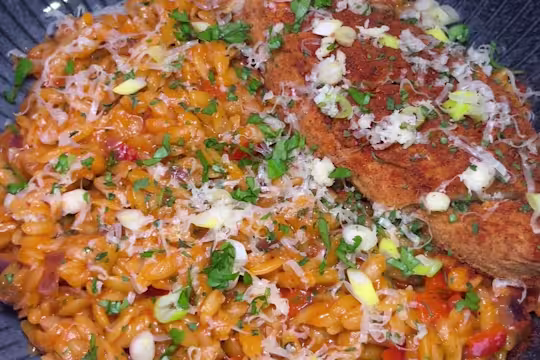 Creamy fajita sauce with orzo pasta served on a blue plate with green garnish, cheese and Quorn Takeaway Buffalo Fillets.