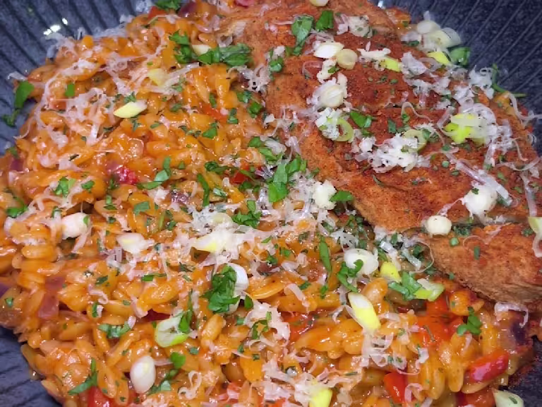 Creamy fajita sauce with orzo pasta served on a blue plate with green garnish, cheese and Quorn Takeaway Buffalo Fillets.