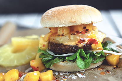 Veggie burger recipe made with Quorn Burgers on top of lettuce garnished with onions, pineapple and mango salsa in a bun