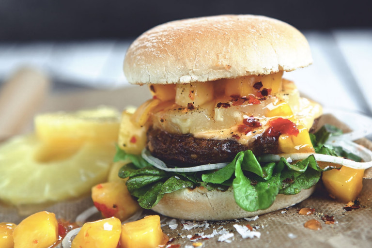 Veggie burger recipe made with Quorn Burgers on top of lettuce garnished with onions, pineapple and mango salsa in a bun