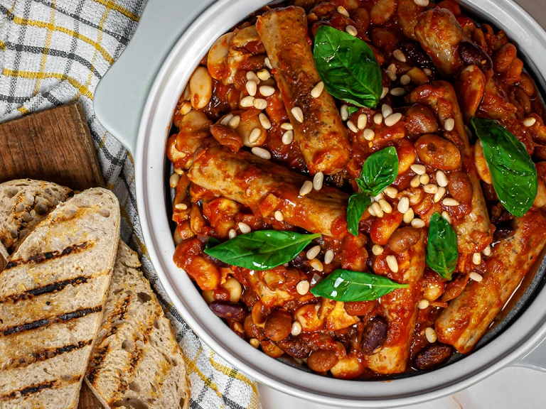 Tuscan sausage on bean stew in a bowl with charred bread on the side