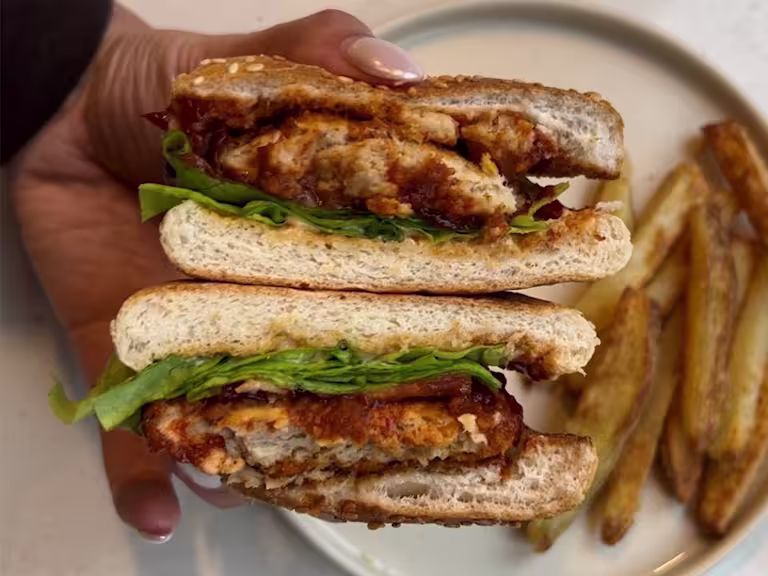 Cross section of Quorn Crunchy Fillet Burger coated in BBQ sauce in a seeded burger bun with lettuce, tomato and mayonnaise.