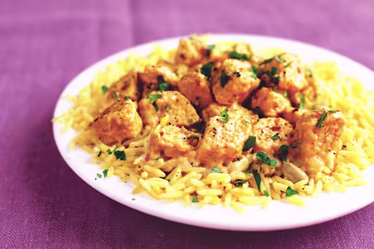 A serving of Quorn Vegetarian Korma on top of a bed of rice served on a white dish.