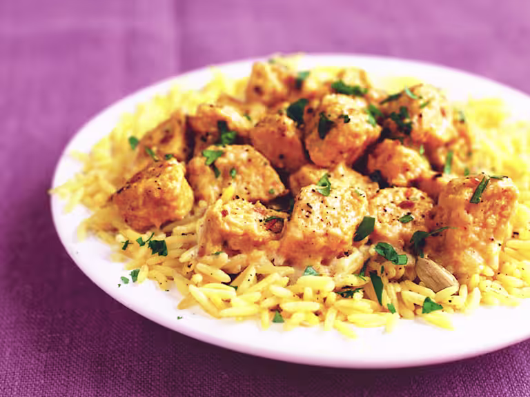 A serving of Quorn Vegetarian Korma on top of a bed of rice served on a white dish.
