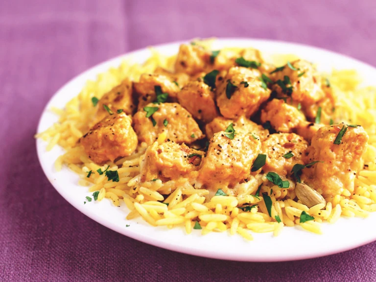 A serving of Quorn Vegetarian Korma on top of a bed of rice served on a white dish.